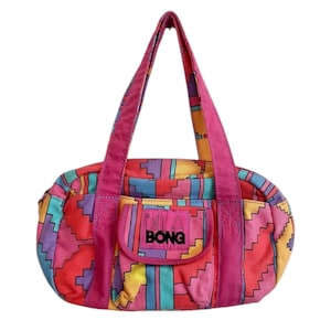 May include: A pink and multi-coloured tote bag with a Billabong logo. The bag has a geometric pattern and a small front pocket.