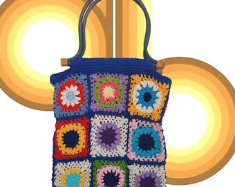 May include: A blue crocheted tote bag with colorful square patches. The bag has wooden handles.