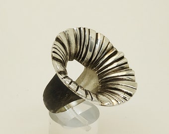 May include: A silver ring with a unique design that resembles a flower. The ring is on a white display stand.