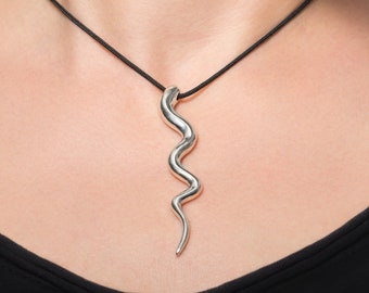 May include: A silver snake pendant necklace on a black cord. The pendant is long and thin, with a wavy design.