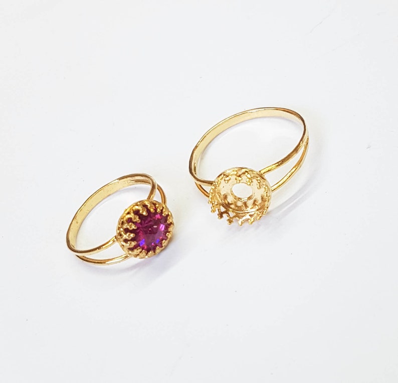 May include: Two gold rings with a bezel setting. One ring has a purple stone in the setting.