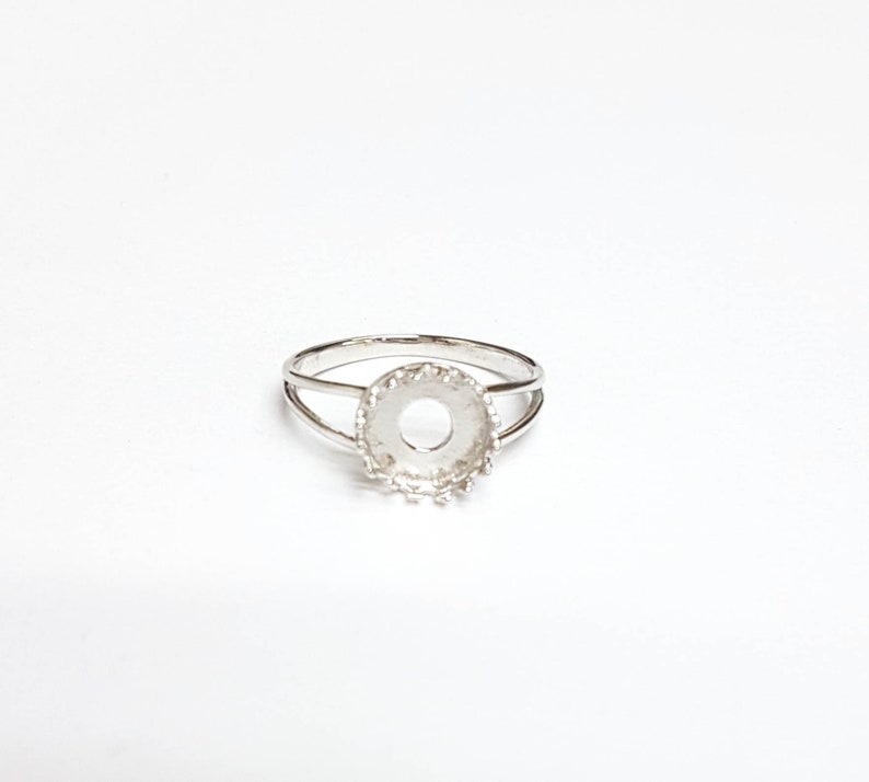May include: Silver ring with a round bezel setting. The bezel is designed with a decorative edge.