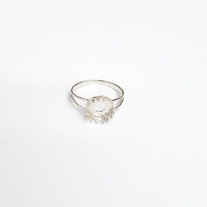 May include: Silver ring with a round bezel setting. The bezel is designed with a decorative scalloped edge.