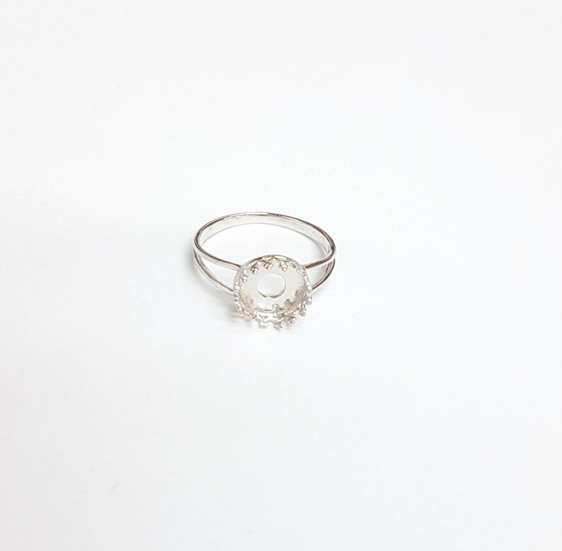 May include: Silver ring with a round bezel setting. The bezel is designed with a decorative scalloped edge.