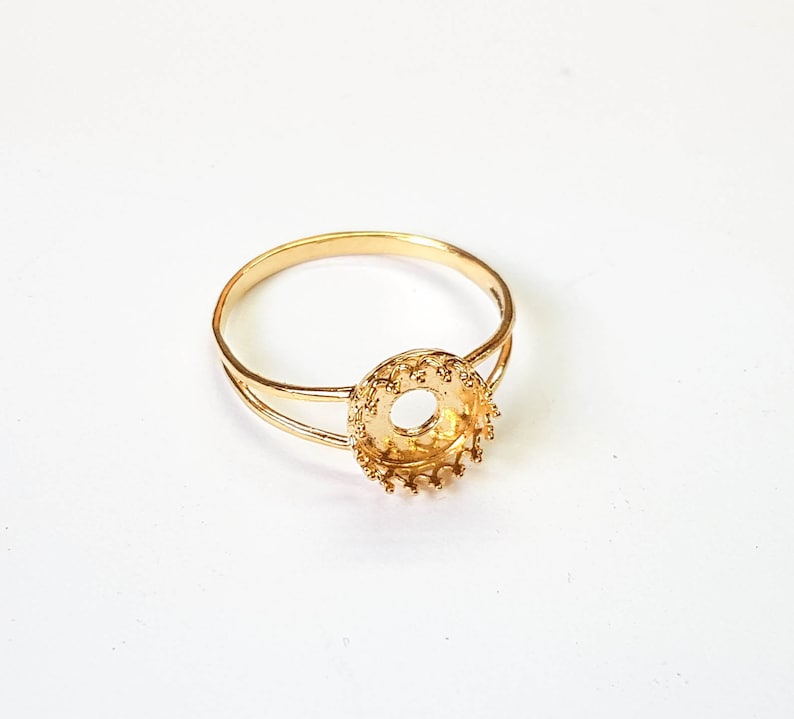 May include: A gold ring with a round bezel setting. The bezel is designed with a decorative edge.