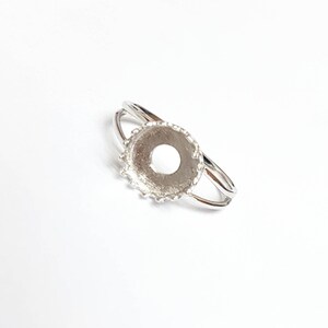 May include: Silver ring setting with a round bezel, ready to be filled with a gemstone or other embellishment.