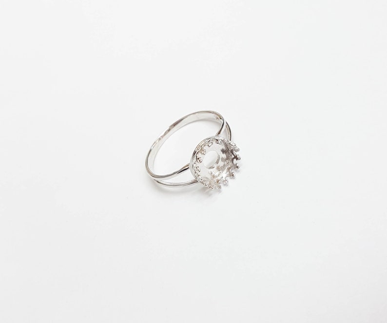 May include: A silver ring with a round bezel setting. The bezel is open and ready to be filled with a stone or other embellishment.