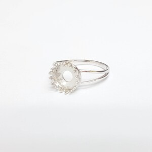 May include: Silver ring with a round bezel setting. The bezel is decorated with a scalloped edge.