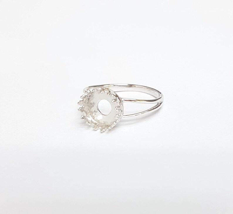 May include: Silver ring with a round bezel setting. The bezel is decorated with a scalloped edge.