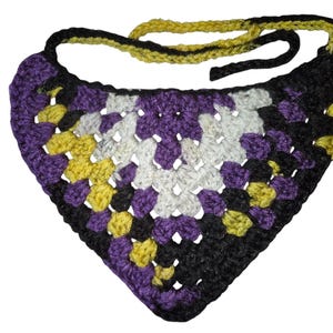 Könnte beinhalten: Ein handgehäkeltes Bandana im Granny-Square-Muster. Das Bandana hat ein Farbschema aus Lila, Schwarz, Gelb und Weiß. Der Nackenriemen ist gelb und schwarz. Dieses Accessoire ist für Haustiere geeignet.