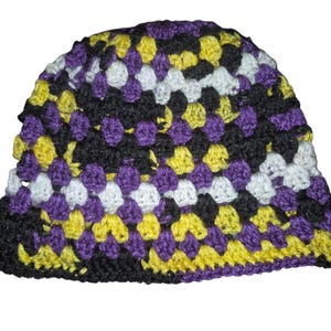 Könnte beinhalten: Ein handgehäkelter Hut im Granny-Square-Muster. Der Hut hat ein Farbschema aus Schwarz, Lila, Gelb und Weiß. Der Hut ist im Beanie-Stil gehalten und eignet sich für kaltes Wetter und Freizeitkleidung.