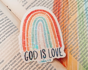 May include: A rainbow sticker with glitter accents and the text "God is Love 1 John 4:8" on a page of a book.