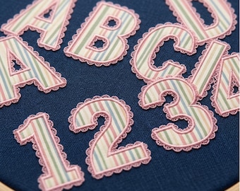 May include: Embroidered alphabet letters and numbers with a multi-colored vertical stripe pattern and pink scalloped edges. The text 5 Sizes - 2", 2.5", 3", 3.5", 4" and JEF - PES - PEC - EXP - VIP - VP3 - DST - XXX are visible.