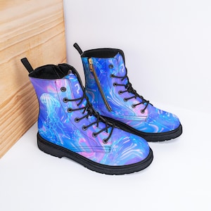 Könnte beinhalten: Ein Paar Kampfstiefel mit einem lebendigen blauen, lila und rosa Quallen-Design. Die Stiefel haben schwarze Sohlen, schwarze Schnürsenkel und einen seitlichen Reißverschluss. Die Stiefel sind aus strapazierfähigem Material gefertigt.