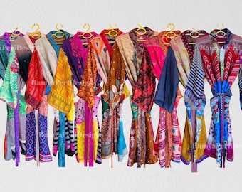 May include: A collection of colorful, patterned robes hanging on yellow hangers against a white wall. The robes display a variety of colors, including blue, red, pink, and yellow, with floral and geometric designs. The robes are made of a lightweight fabric.