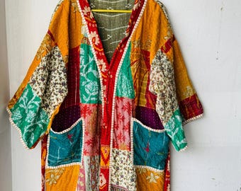 May include: A patchwork kimono-style robe in a variety of colors, including yellow, red, green, and teal. The robe features a V-neck, two pockets, and a tie belt. The fabric has a floral and geometric pattern.