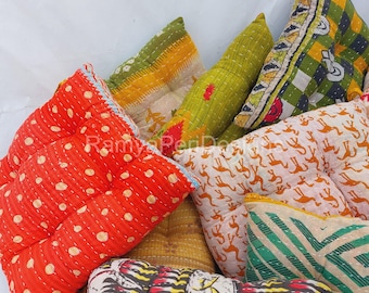 May include: A collection of colorful, patterned floor cushions. The cushions are made of fabric with various designs, including polka dots, geometric patterns, and floral motifs. The cushions are arranged in a pile, with some overlapping.
