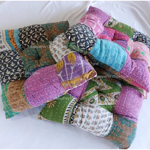 Könnte beinhalten: Vier farbenfrohe Patchwork-Bodenkissen mit verschiedenen floralen und geometrischen Mustern. Die Kissen sind aus recycelten Saris hergestellt und perfekt, um jedem Raum einen Hauch von Boho-Stil zu verleihen.