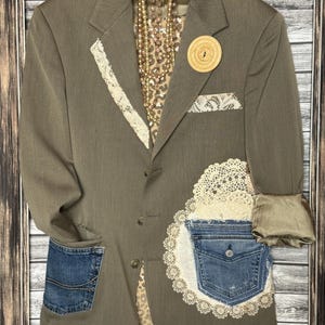 Könnte beinhalten: Olivgrüner Blazer mit Jeans-Taschen und Spitzenbesatz. Der Blazer hat ein Leopardenmuster-Futter, einen Holzknopf und dekorative Spitzenborte. Die Ärmel sind umgeschlagen, und eine Perlenkette hängt an der Aufhängung.