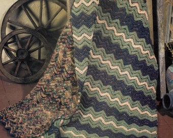 May include: A crocheted blanket with a chevron pattern in shades of green, blue, and beige. The blanket is draped over a wooden wheel.