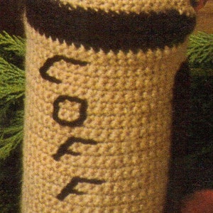 May include: A crocheted coffee bean container with a brown and beige striped pattern. The word "COFFEE" is crocheted into the front of the container.