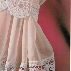 May include: White sheer curtain with a white crocheted lace trim. The lace trim has a scalloped edge and a delicate floral pattern.