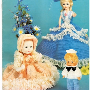 May include: A vintage book cover titled "CROCHET FESTIVAL" featuring a collection of crochet dolls. The dolls include a baby doll in a peach dress, a doll in a blue dress, and a sailor doll. The background is light blue.