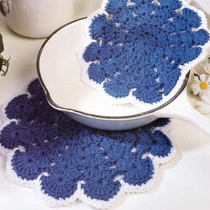 Pode incluir: Dois pegadores de panela de crochê azul e branco com borda festonada. Os pegadores de panela são feitos com um padrão de ponto simples e são perfeitos para proteger as superfícies de pratos quentes.