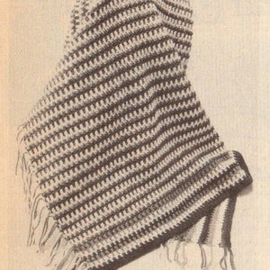 Op de afbeelding: Een gehaakte capuchon sjaal met een gestreept patroon in wit en bruin. De sjaal heeft een franje rand en is gebonden met een lange kwast.