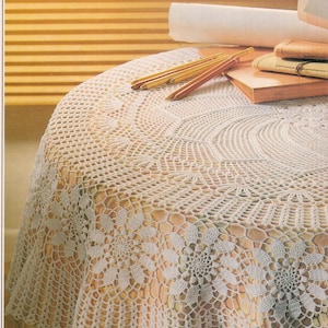 May include: White crocheted tablecloth with a delicate floral pattern. The tablecloth has a scalloped edge and is made with a fine yarn.