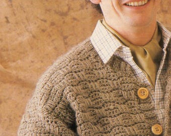 May include: A textured, light brown cardigan with large wooden buttons. The cardigan is worn over a collared shirt with a plaid pattern and a solid green shirt. The person is smiling.