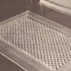 Puede incluir: Alfombra rectangular beige con un centro texturizado con diseño de diamantes y un borde tejido. La alfombra parece hecha a mano, posiblemente crochetada o tejida, y es adecuada para la decoración del hogar. La alfombra mide aproximadamente 91 cm de largo y 61 cm de ancho.