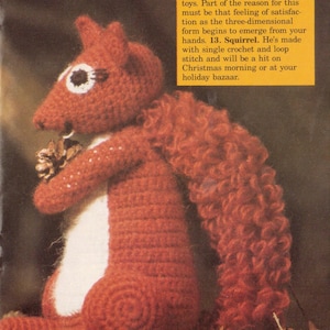 May include: A crocheted squirrel toy in shades of red and white, holding a pinecone. The squirrel has a fluffy tail and is made with single crochet and loop stitch. Text on the image reads: "Add this cute little fellow to your crocheted zoo."