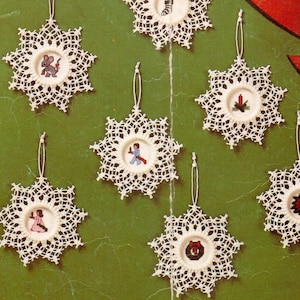 May include: Seven white crocheted snowflake ornaments with different embroidered designs in the center. The designs include a mouse, a man in a blue suit, a candle, a poinsettia, a wreath, and two angels.