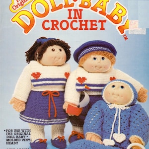 May include: A vintage crochet pattern book cover titled "Doll Baby in Crochet." The cover features three crocheted dolls wearing white and blue outfits. The text on the cover includes "The Original" and "Only 4 Basic Stitches Used!!"