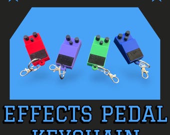 May include: Four miniature effects pedal keychains in red, purple, green, and blue. Each keychain has a black knob and a silver key ring.
