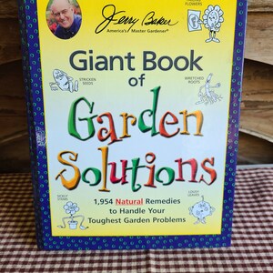 May include: A hardcover book titled "Giant Book of Garden Solutions" by Jerry Baker, America's Master Gardener. The cover is yellow with green, orange, and blue text and illustrations of garden problems.