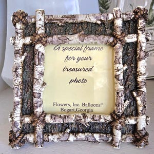 May include: A rustic photo frame with a birch bark design. The frame features a natural wood texture with rope accents and the text "A special frame for your treasured photo". The frame is from Flowers, Inc. Balloons, Bogart, Georgia.