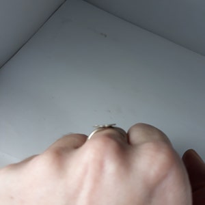 May include: A silver ring with a flower design.