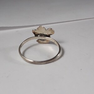 May include: A silver ring with a flower design. The ring is simple and elegant.