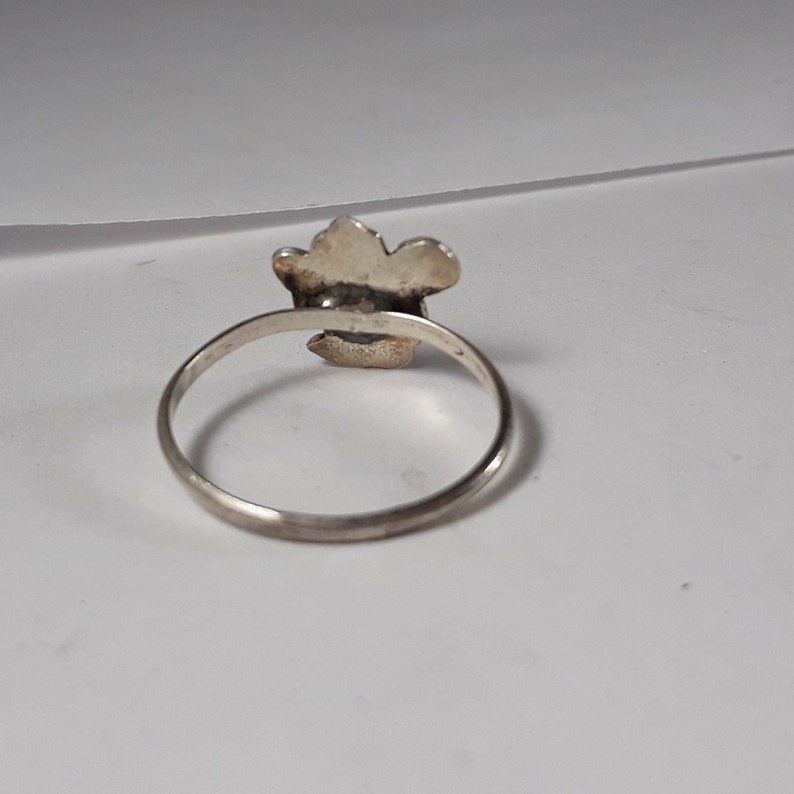 May include: A silver ring with a flower design. The ring is simple and elegant.