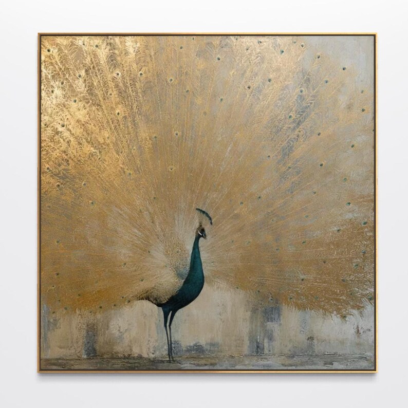 Op de afbeelding: Een vierkant wandkunstwerk met een pauw met een donkerblauwe nek en lichaam, die een grote, uitgestrekte staartwaaier toont in metallic bladgoud. De achtergrond heeft een getextureerde, neutrale grijstint en het geheel is ingelijst in goud.