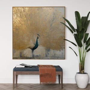 Op de afbeelding: Een vierkant wandkunstwerk met een pauw met een grote, uitgewaaierde staart in metallic bladgoud. Het lichaam van de pauw is diep blauwgroen en staat tegen een getextureerde achtergrond in neutrale tinten. Het kunstwerk heeft een dunne gouden rand.