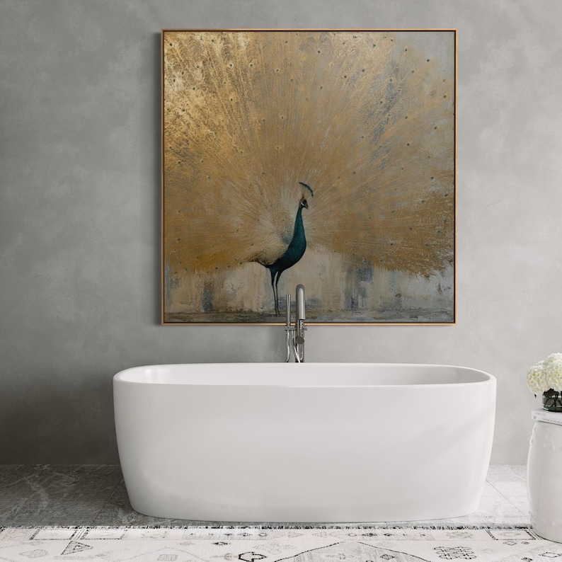 Textured gold foil peacock artwork hanging on a gray concrete wall above a freestanding white bathtub. Luxury bathroom wall decor idea.