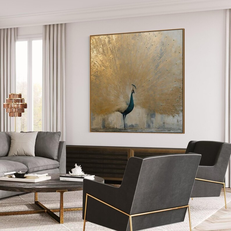Modern gold peacock painting styled above a couch in a chic living room with gray armchairs and a coffee table. Large scale wall decor inspiration.