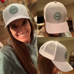 May include: A gray and white baseball cap with a green and white logo that says "Tomco Designs" on the front. The logo is a circular design with a saw blade in the center.