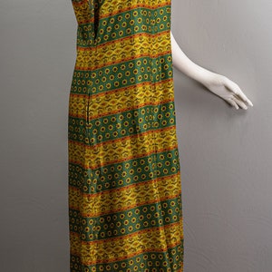 May include: A sleeveless maxi dress with a green and yellow geometric pattern. The dress has a round neckline and a straight silhouette.