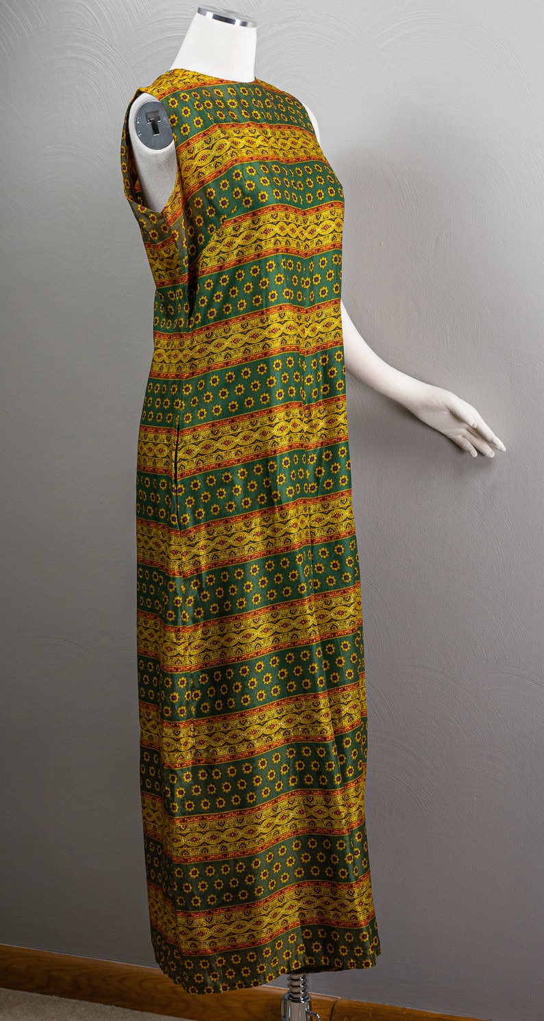 May include: A sleeveless maxi dress with a green and yellow geometric pattern. The dress has a round neckline and a straight silhouette.