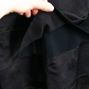 May include: Black skirt with a layered design. The skirt is made of a sheer fabric with a solid black lining. The layers are separated by thin gold stitching.
