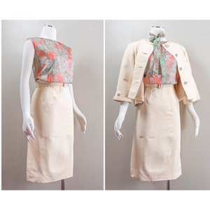 May include: A vintage two-piece outfit featuring a cream-colored pencil skirt and a floral top with a matching belt. The outfit is shown with and without a cream-colored jacket with three-quarter sleeves. The floral top has a green and coral pattern.